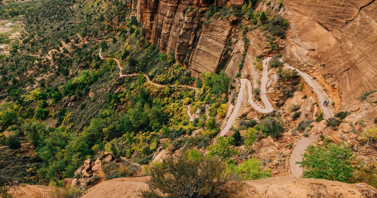 Aerial view of the switchback trail on Angels Landing in Zion National Park, serpentine paths carved into red sandstone cliffs above a green canyon valley