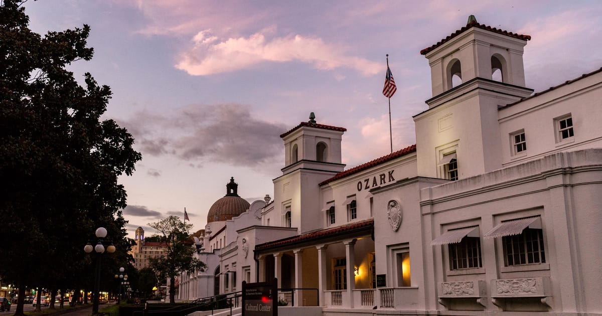 Bathhouse Row at Hot Springs National Park, Arkansas — a line of stately white historic bathhouse buildings beneath a soft pink and lavender sunset sky, the row's columned facades catching the last warm light against the deepening dusk.