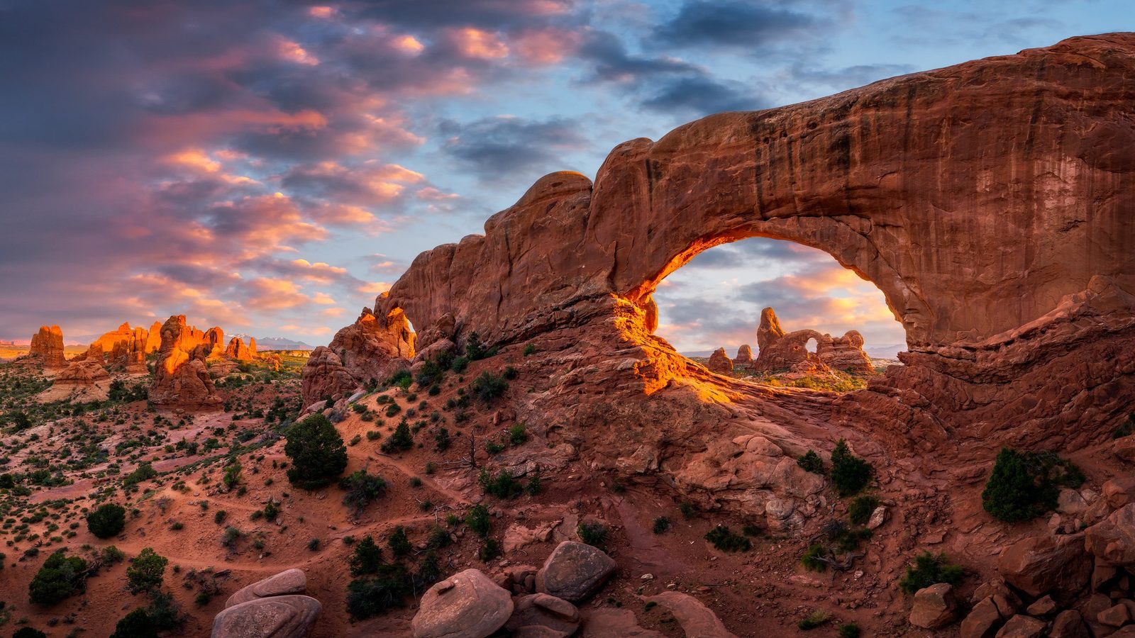 North Window, a massive sandstone arch in the Windows Section of Arches National Park, lit at sunset.