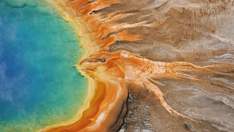 An aerial view of Grand Prismatic Spring in Yellowstone's Midway Geyser Basin, showing the vivid gradient from deep blue at the spring's center to turquoise,…