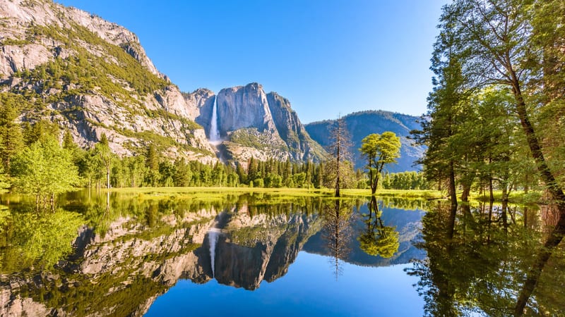 A sweeping high-country granite landscape in Yosemite National Park at twilight, featuring Tenaya Lake nestled among polished granite domes with snow-capped …