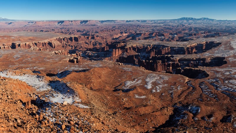 A sweeping panoramic vista from a high mesa overlook in Canyonlands National Park, revealing a vast labyrinth of red sandstone buttes, mesas, and canyon syst…
