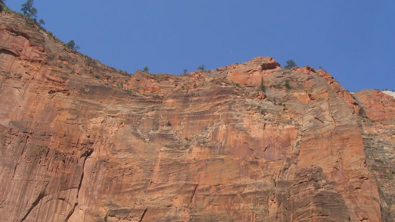 The Virgin River flowing past smooth boulders deep within the red sandstone walls of The Narrows in Zion