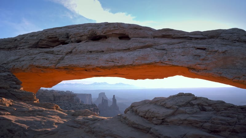 Mesa Arch in Canyonlands National Park frames a dramatic sunrise, with the rising sun casting a brilliant starburst and bathing the underside of the sandston…